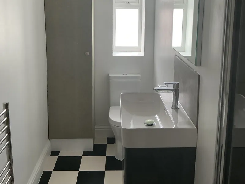 Clean bathroom with a black and white tiled floor, basin and mirror