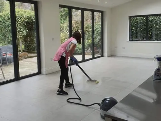 Cleaner steam-mopping the floor of a bright open-plan kitchen extension
