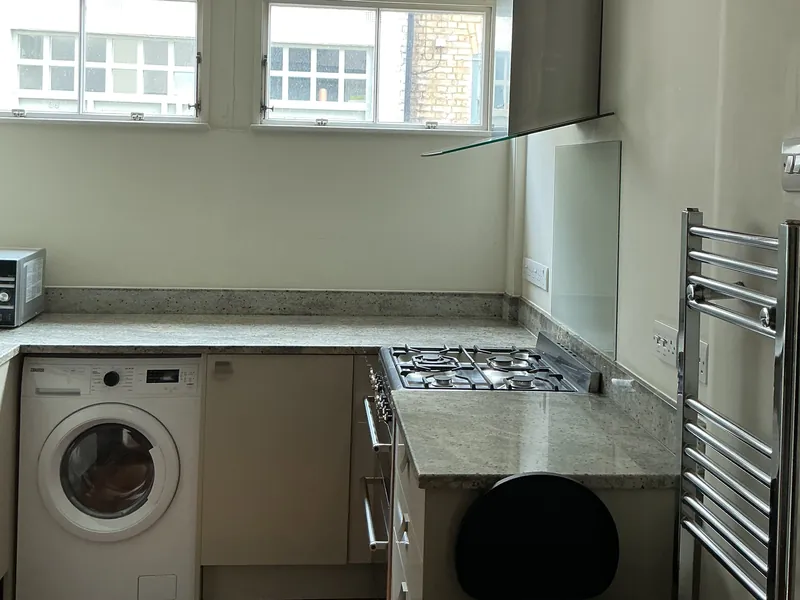 Clean kitchen with a gas hob, granite worktop and washing machine