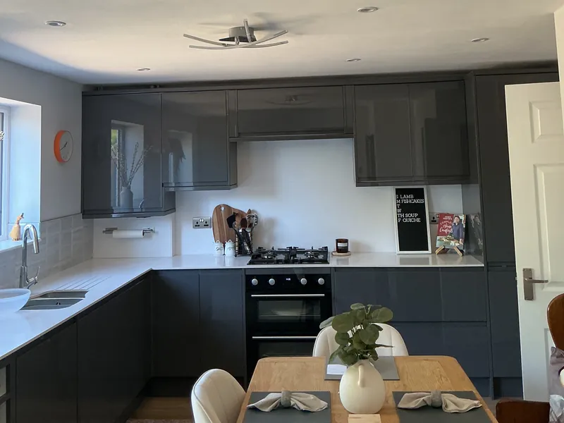 Clean kitchen with dark grey units, a white worktop and a dining table
